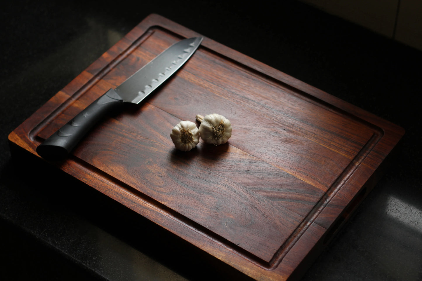 Top view of a thick acacia cutting board with a deep juice groove around the edges.