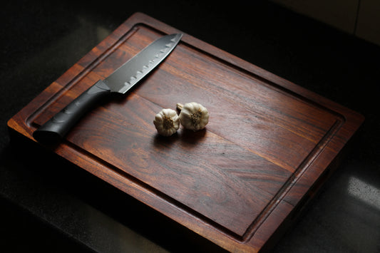 Top view of a thick acacia cutting board with a deep juice groove around the edges.