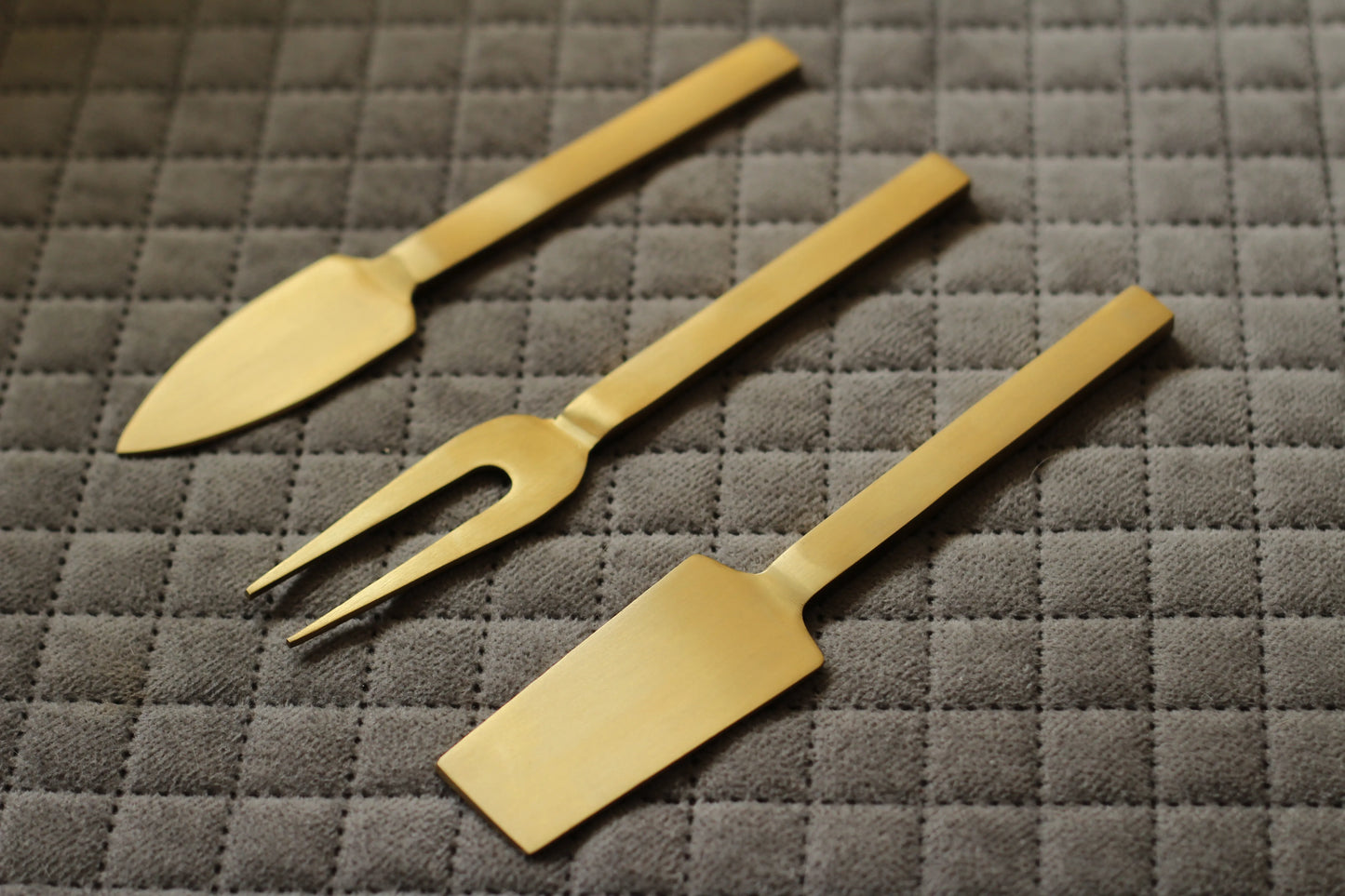 Side angle showing the fine detailing and curved shapes of each knife in the gold set.