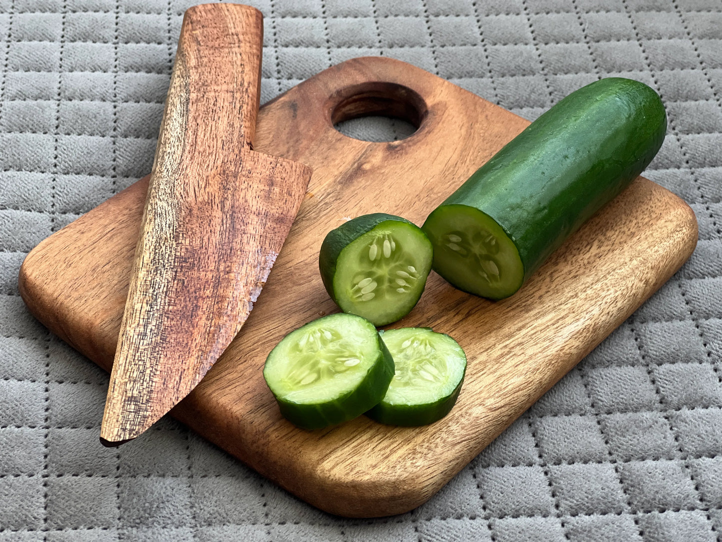 The board and knife set placed on a kitchen counter with cut fruit for child-friendly cooking fun.