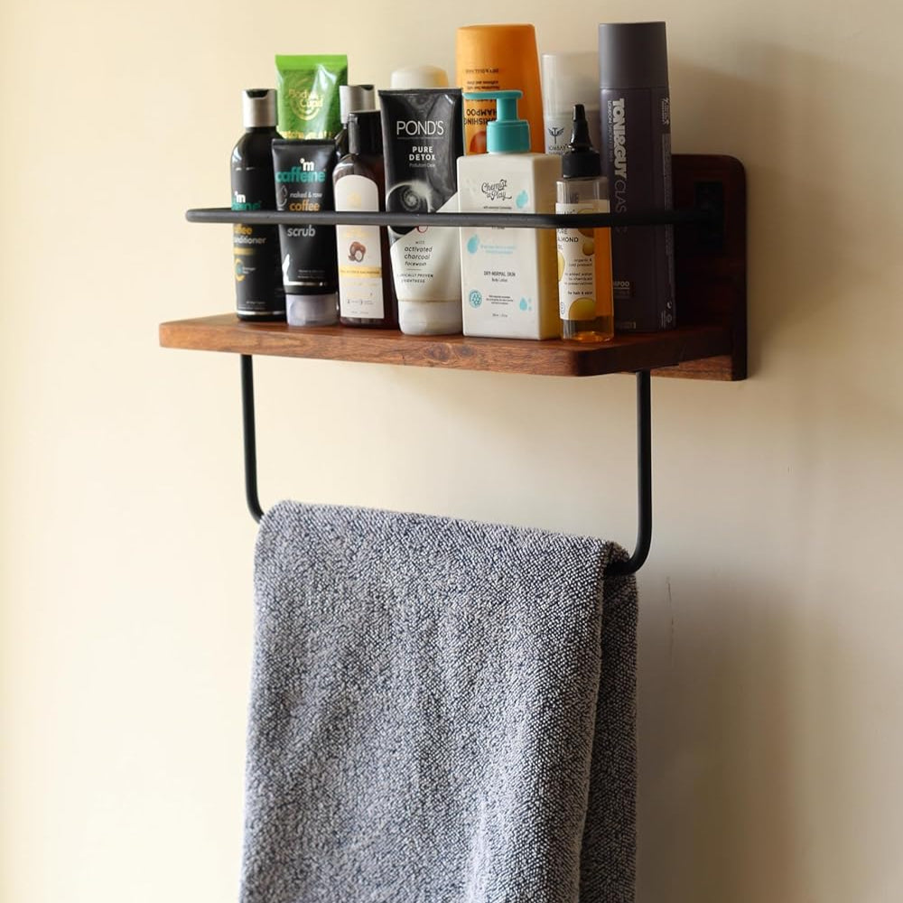 Lifestyle image of the acacia wall rack used in a bathroom holding towels and candles.