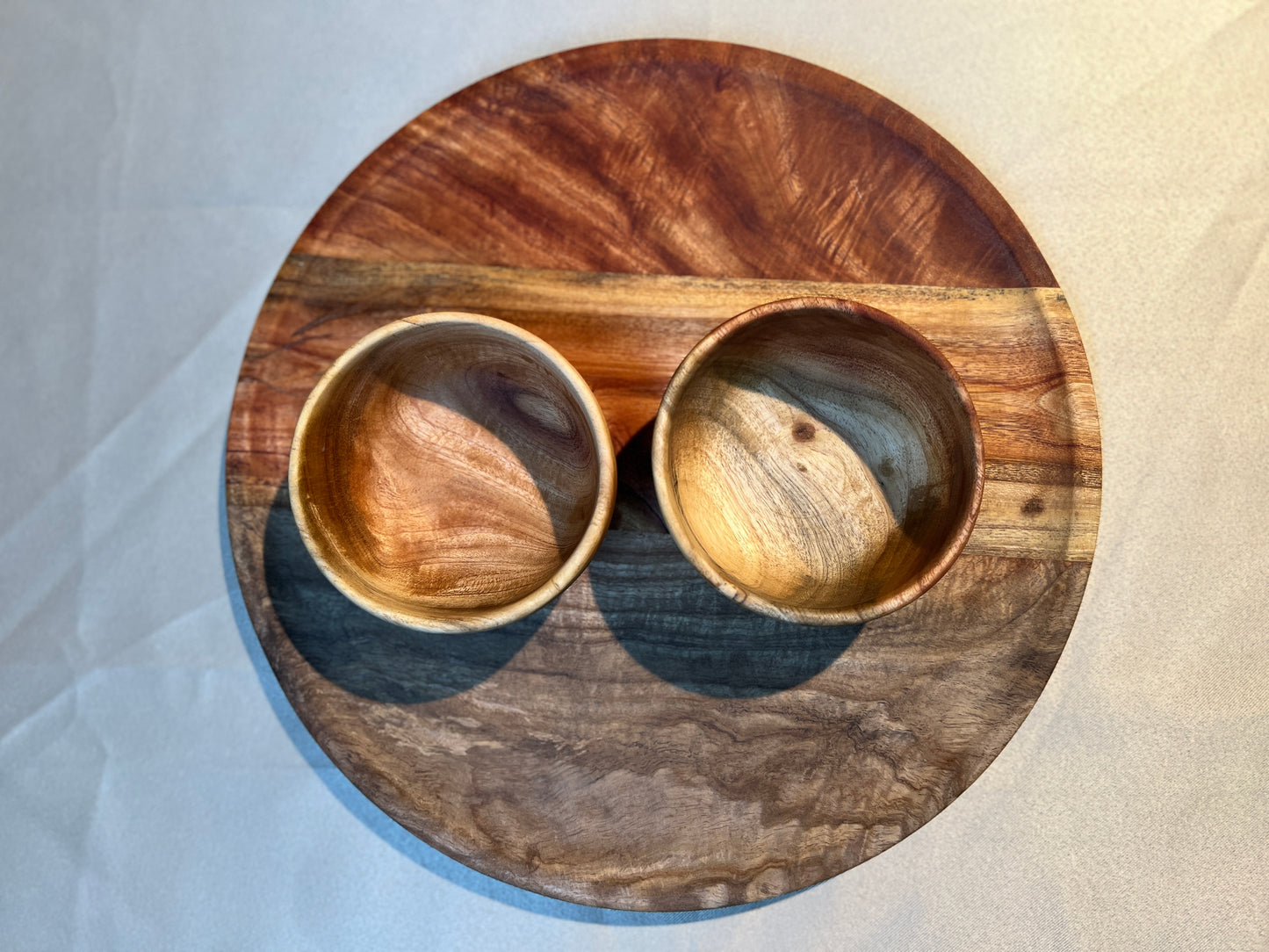 Handcrafted neem wood plate and bowls set on a rustic dining table, styled for a natural kitchen look.
