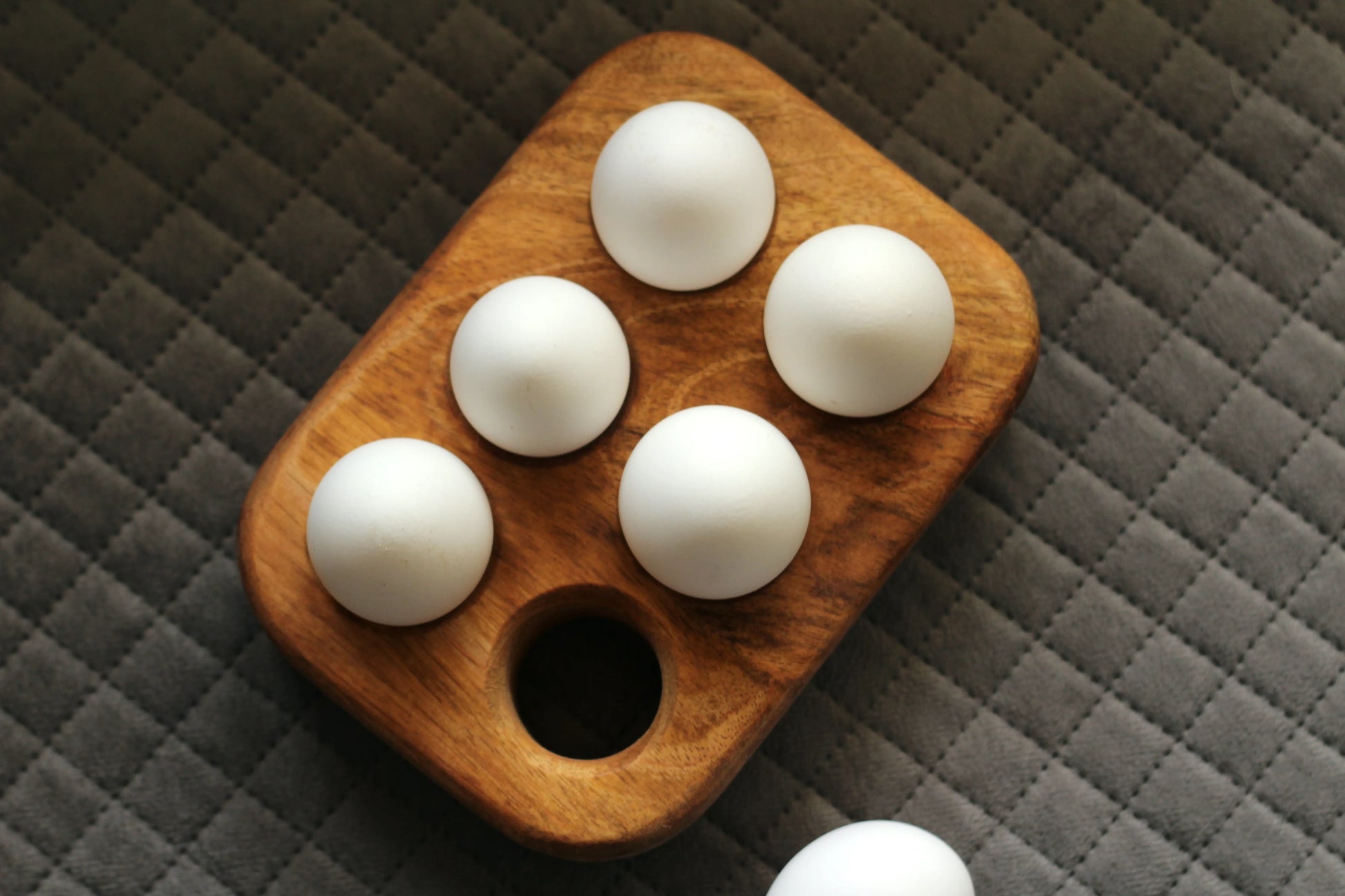 Wooden egg holder placed inside a refrigerator shelf, neatly organizing eggs.