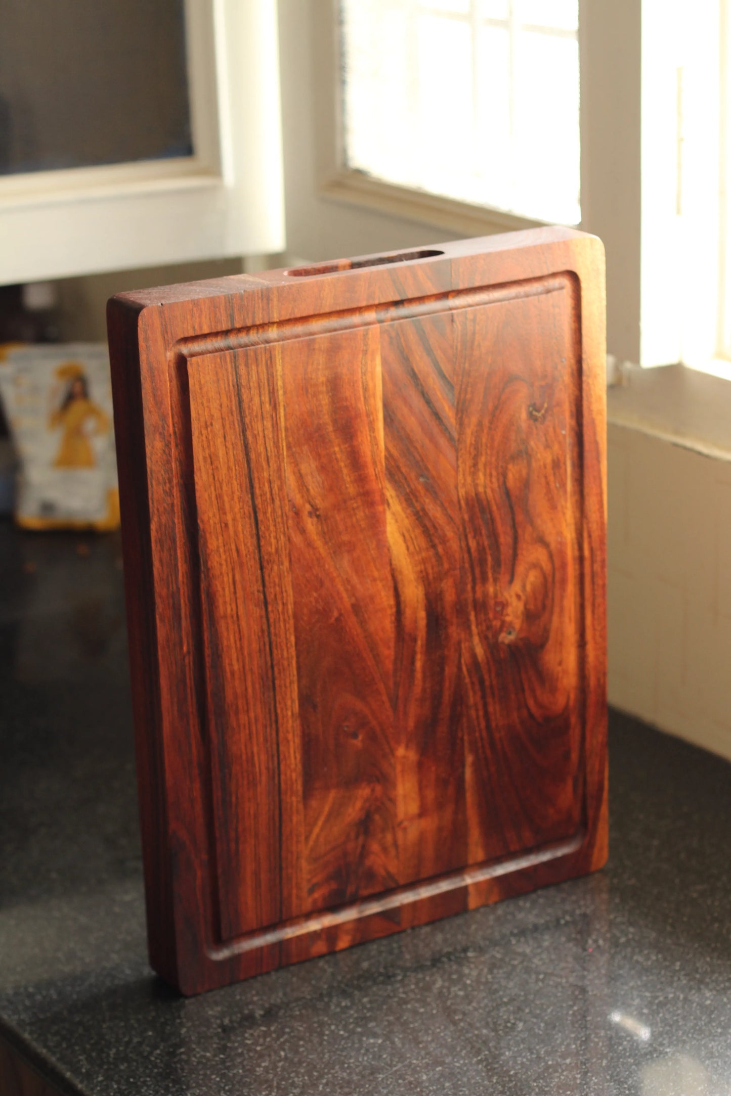 Acacia board used as a serving tray with steak and sliced lemons, utilizing the groove to catch drips.