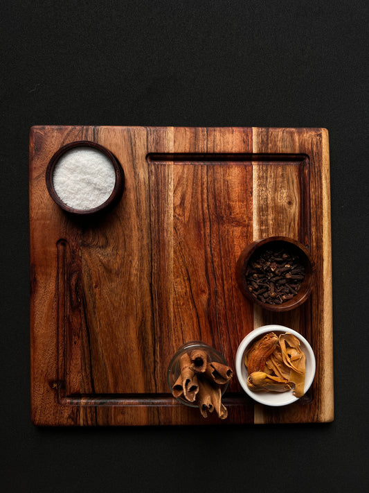 Top view of a square acacia wood platter filled with cheese, grapes, and crackers.