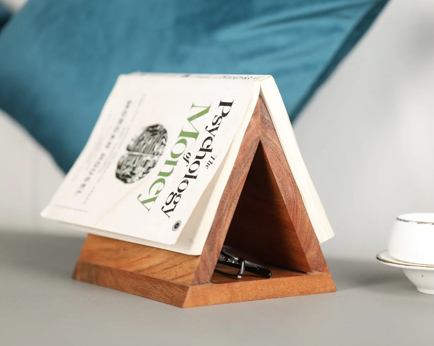 Top view of the acacia wood triangle holder placed on a desk, holding a book open by its pages.
