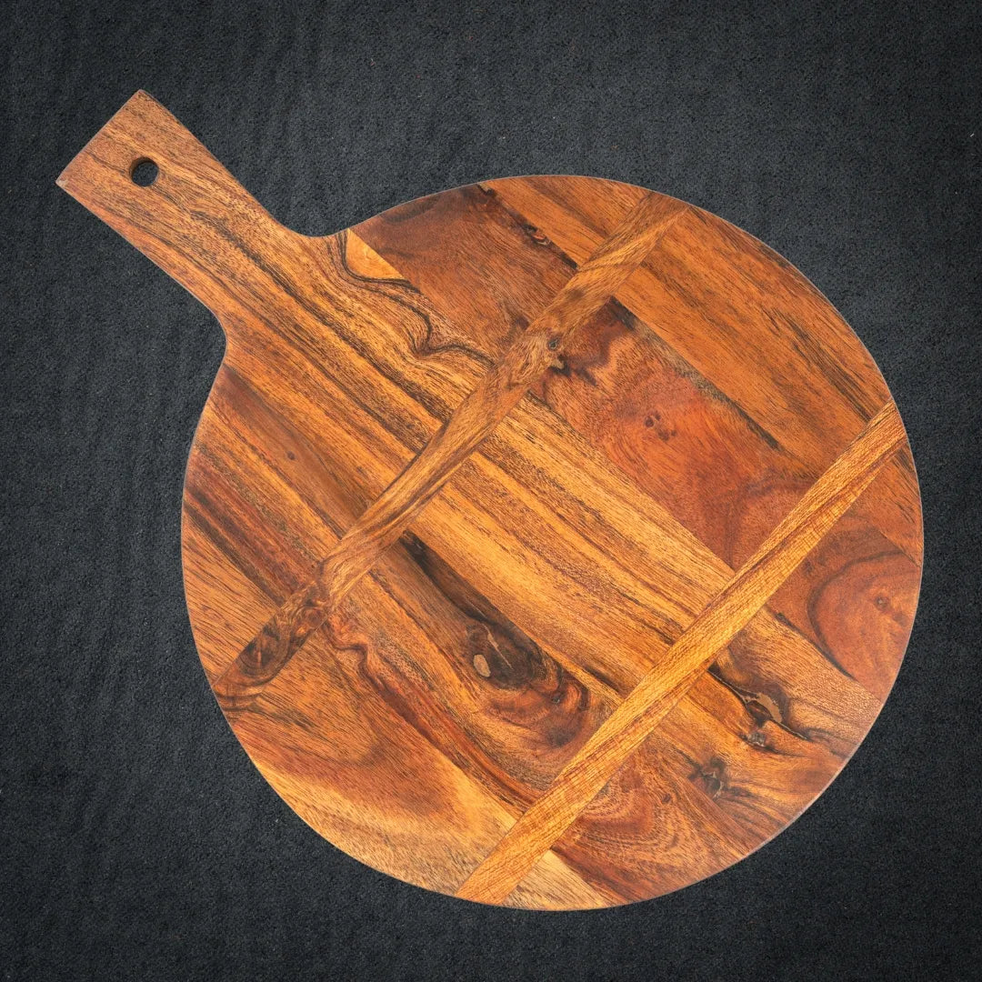 Acacia wood cutting board with European-style curved edges on a kitchen counter.