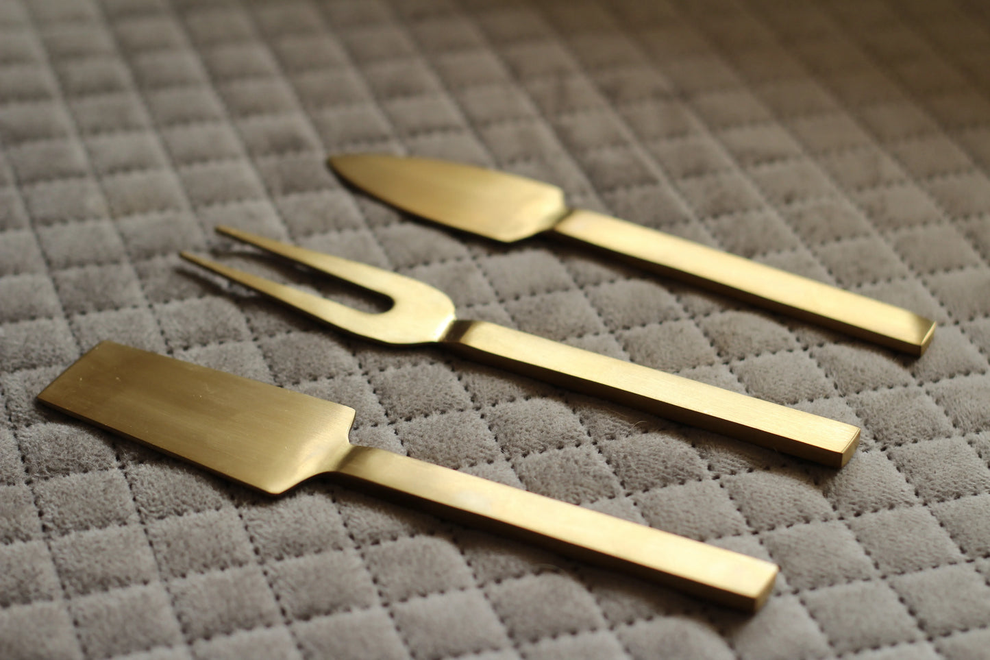 Cheese knife set styled with assorted cheeses and fruits on a wooden serving platter.

