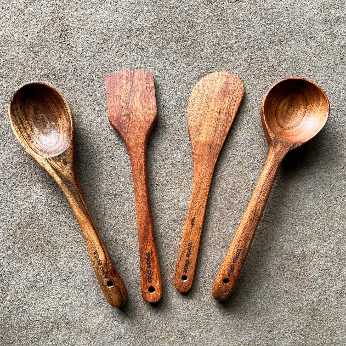 Four wooden spoons on a textured stone surface