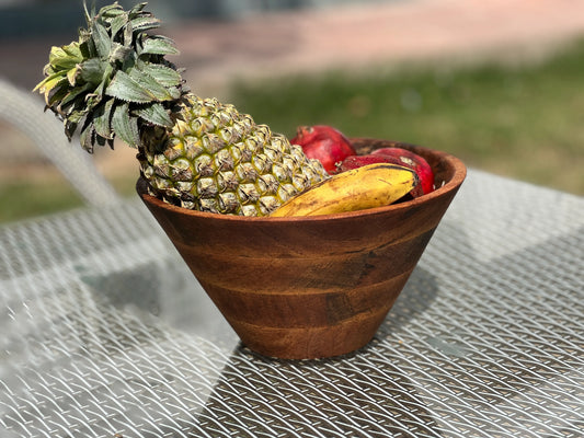Top view of a large mango wood bowl filled with fresh fruits on a kitchen counter.