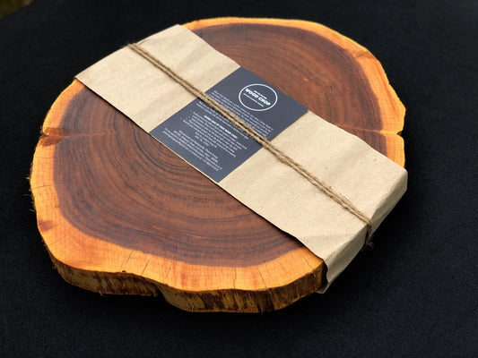 Top view of a round Sheesham wood chopping board with natural live edge and visible grain.