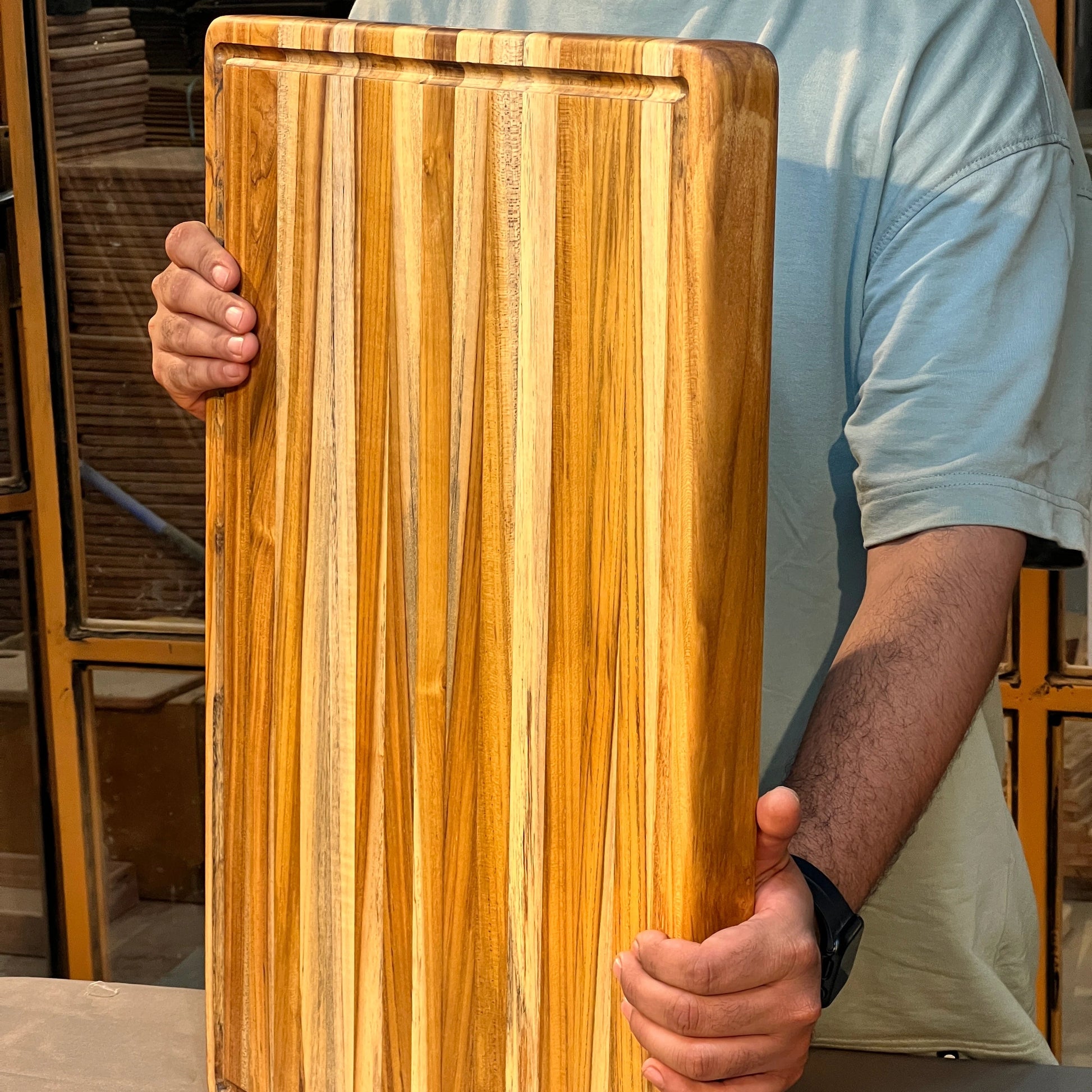  Side profile showing the 1.5-inch thick teak cutting board with smooth edges and rich wood grain.