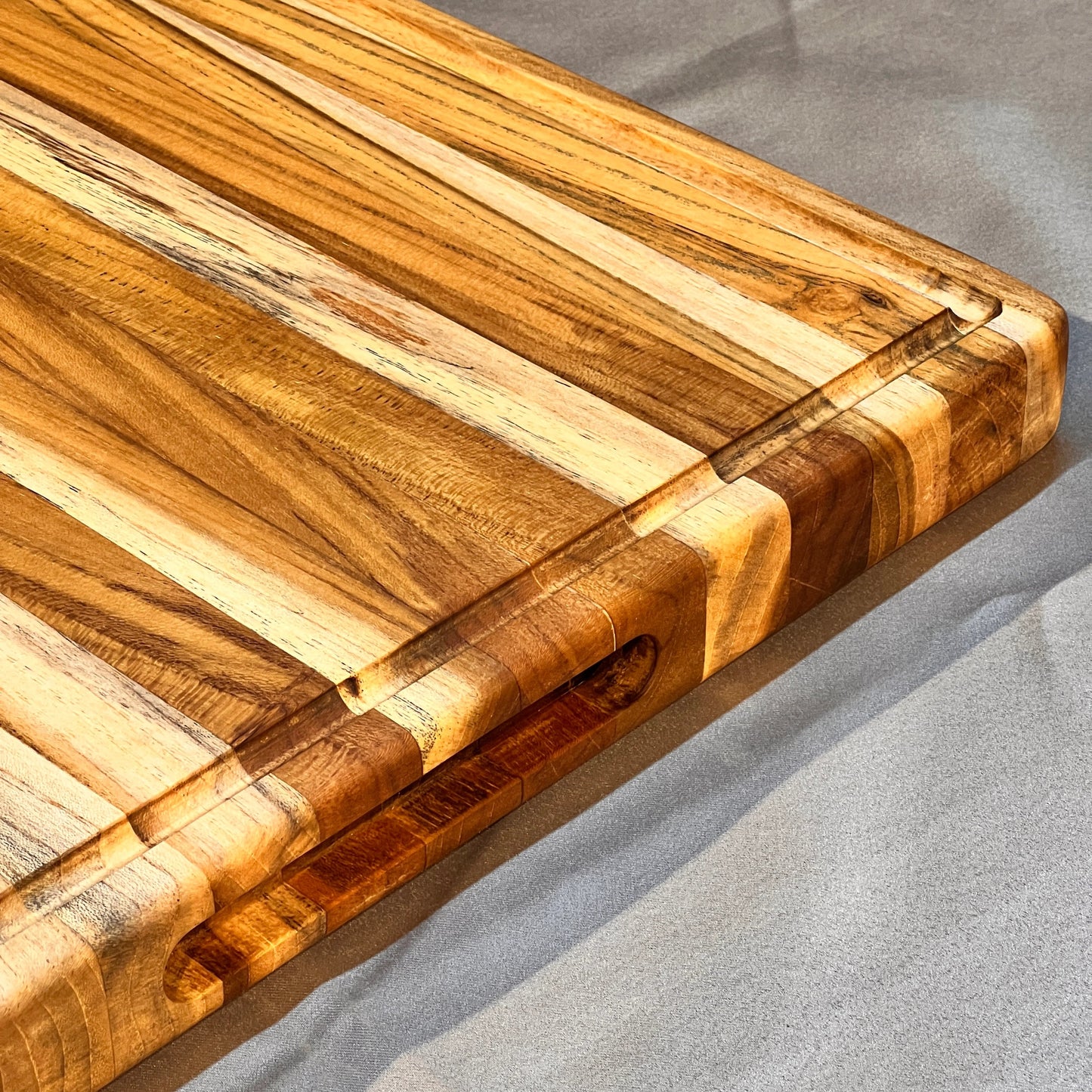  Teak board styled with chopped vegetables and a chef’s knife, highlighting its spacious surface area.