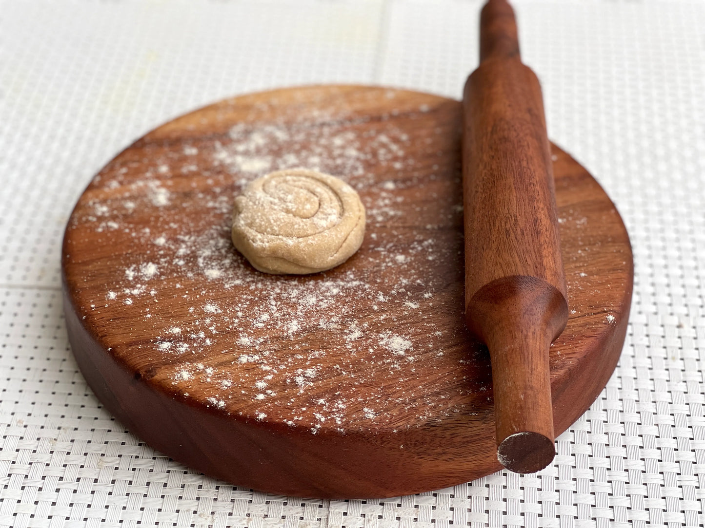 Board and pin set placed on a kitchen counter with flour and dough nearby.