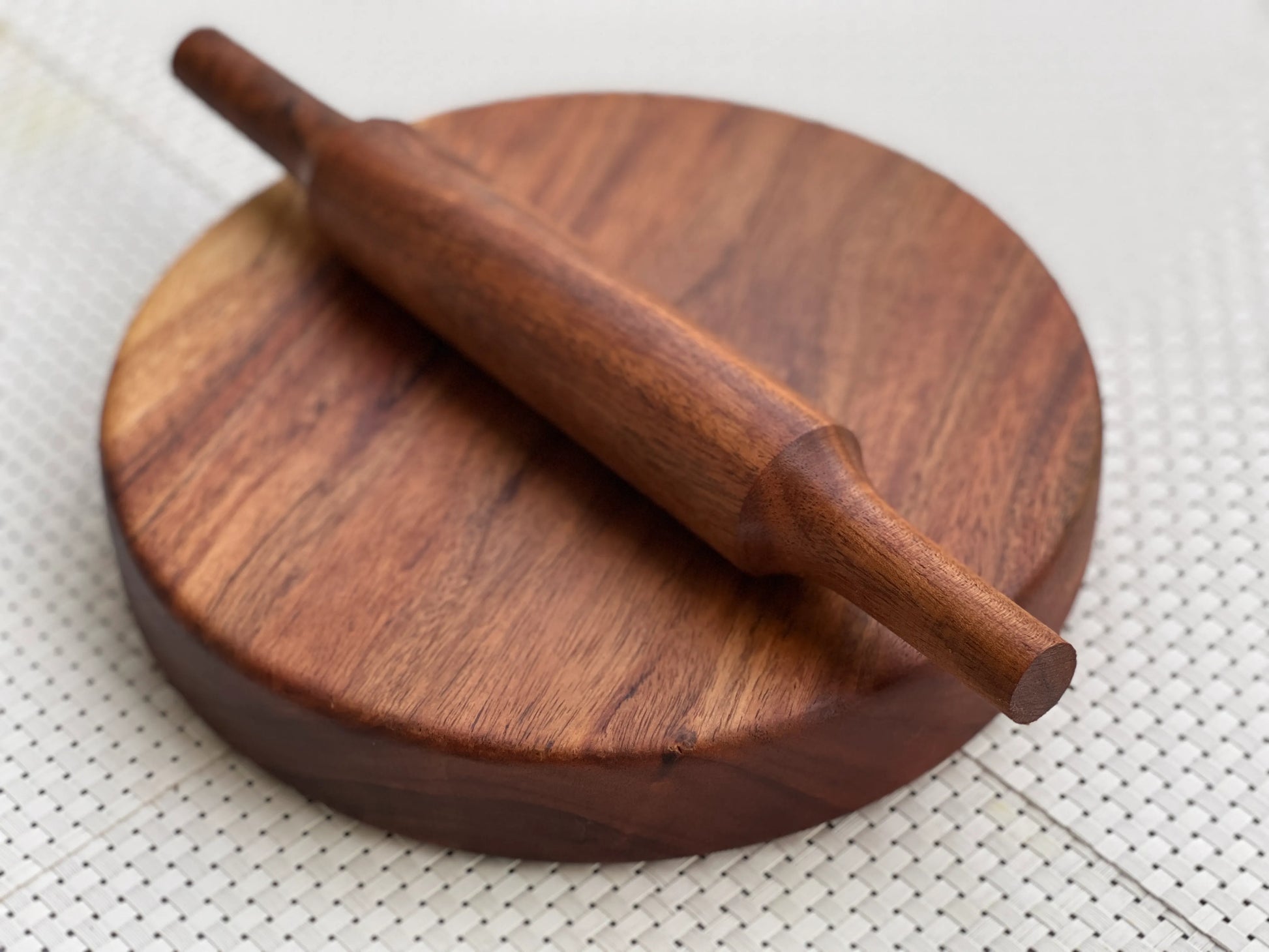 Top view of a round mango wood rolling board with a matching wooden rolling pin placed on top.