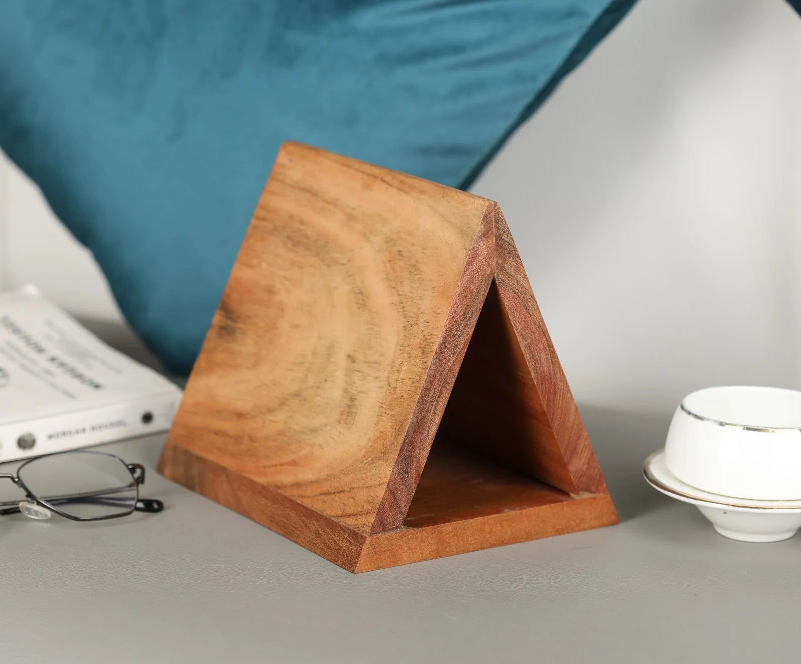  Side angle of the triangular stand with a pair of glasses resting neatly on the angled surface.