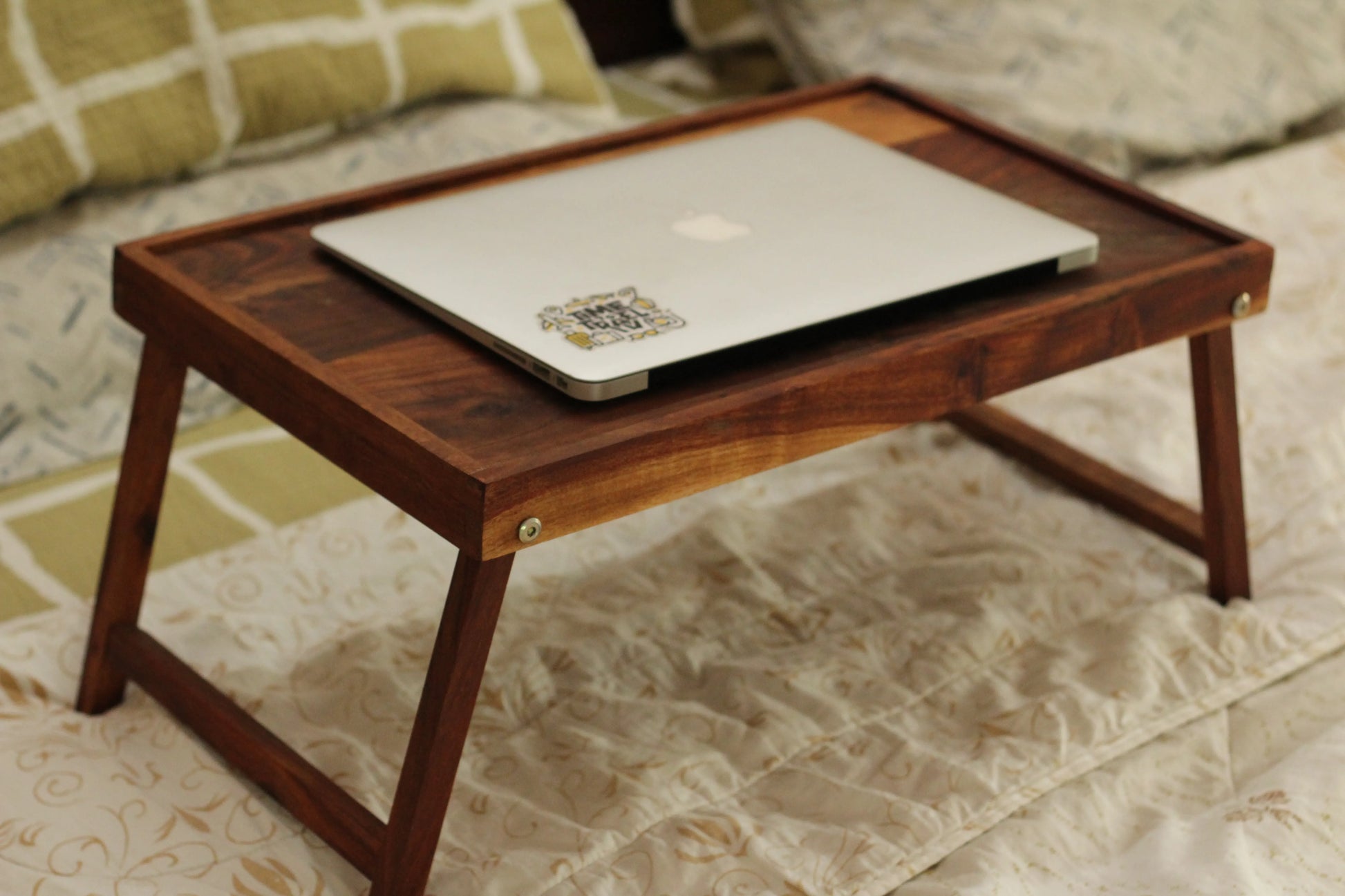 Minimalist lap table placed beside a couch with a book and reading glasses.