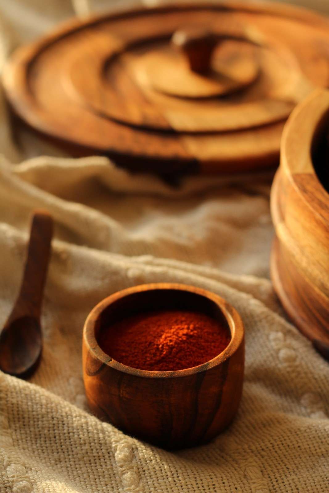 Wooden bowl with red powder on a textured fabric background